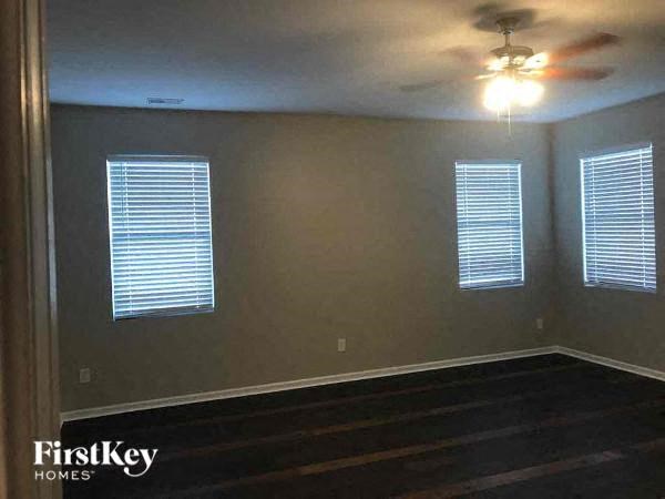an empty room with a ceiling fan and three windows