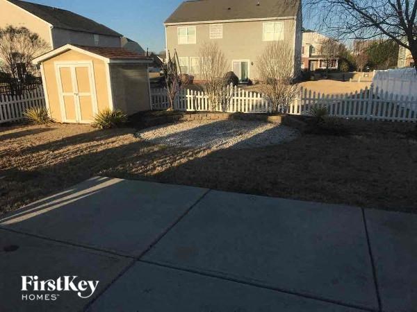 a sidewalk in front of a house with a white fence