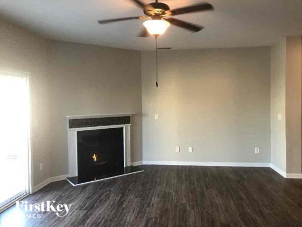 an empty living room with a ceiling fan and a fireplace