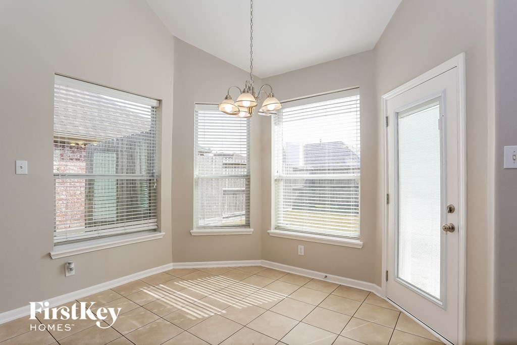 an empty living room with three windows and a chandelier