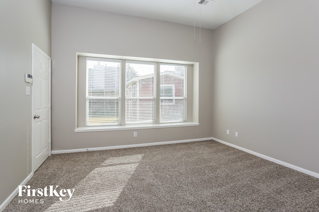 an empty room with a large window and carpet