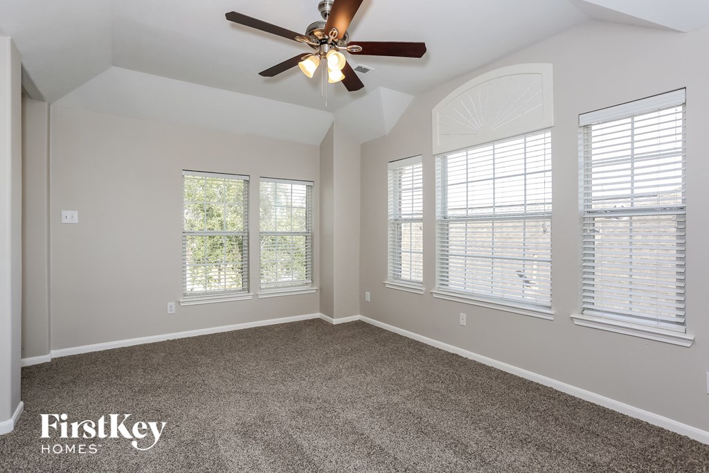 an empty room with a ceiling fan and three windows