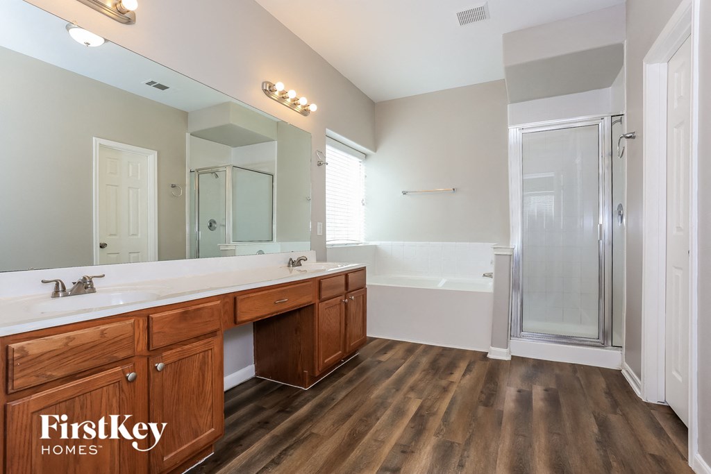 the master bathroom has a large vanity with two sinks and a walk in shower