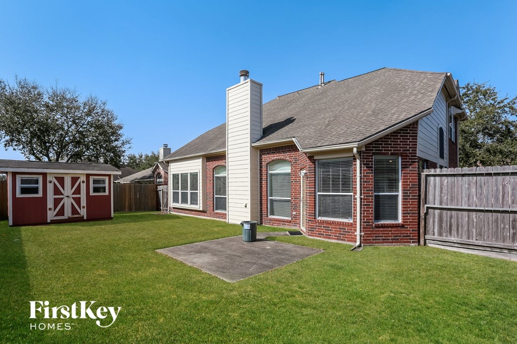 a backyard with a brick house and a red barn