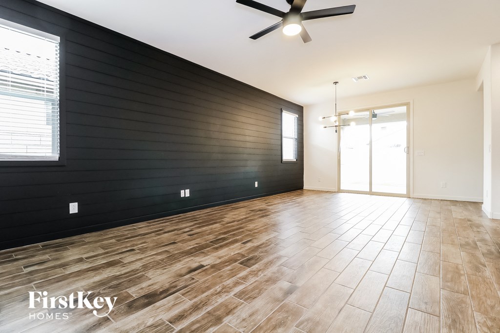 an empty living room with a black accent wall and wood floors