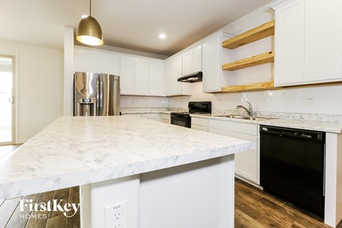 a kitchen with white marble counter tops and black appliances and white cabinets