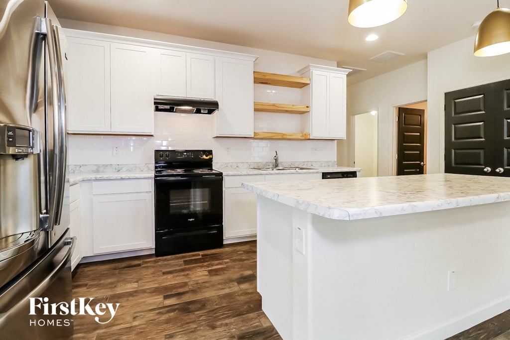 a kitchen with white cabinets and black appliances and a white counter top