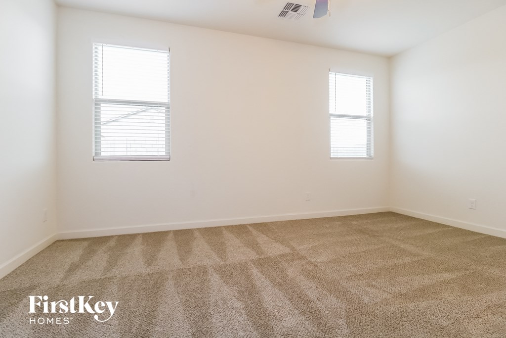 a room with carpet and two windows
