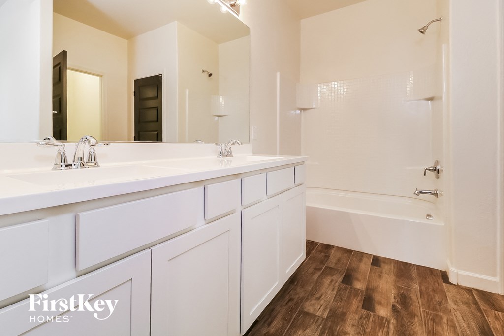 a bathroom with two sinks and a tub and a mirror