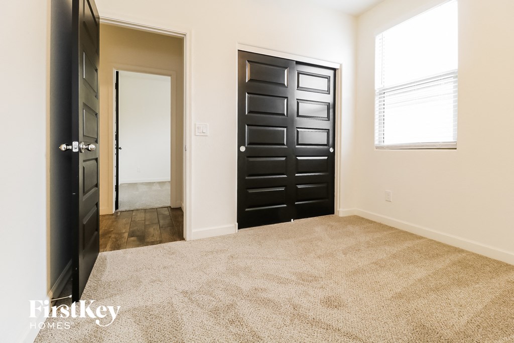 a room with a carpeted floor and black doors and a window