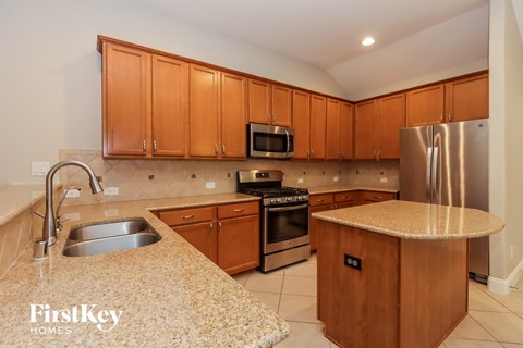 A kitchen with wooden cabinets and a stainless steel refrigerator.