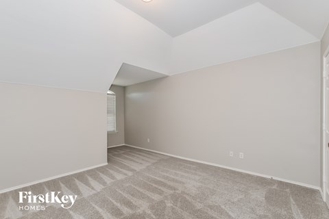A spacious room with a carpeted floor and a skylight.