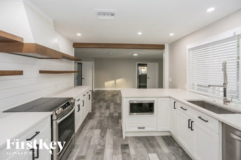 A modern kitchen with white cabinets and a checkered floor.