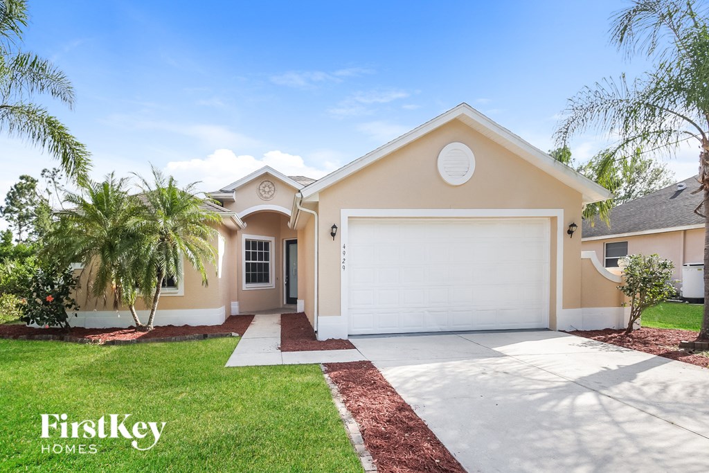 a beige house with a white garage door and a palm tree
