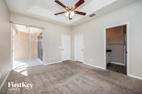 a spacious living room with carpet and a ceiling fan