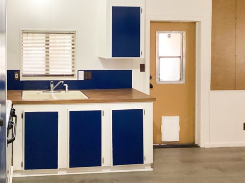 A kitchen with blue and white cabinets and a wooden counter.