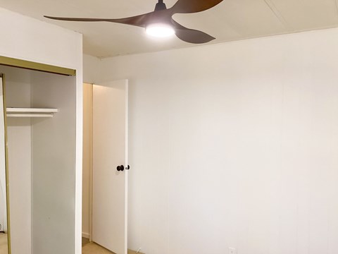 A room with a ceiling fan and a door.