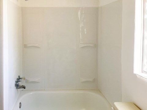 A white bathroom with a tub and a window.