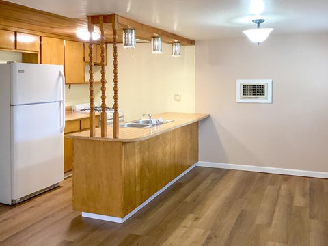 A kitchen with a white refrigerator and wooden cabinets.