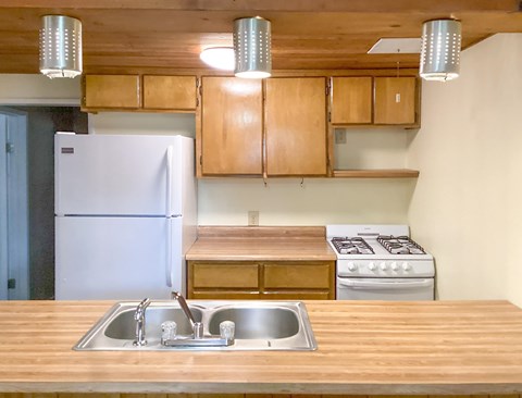 A kitchen with a white refrigerator, wooden cabinets, and a stove top oven.