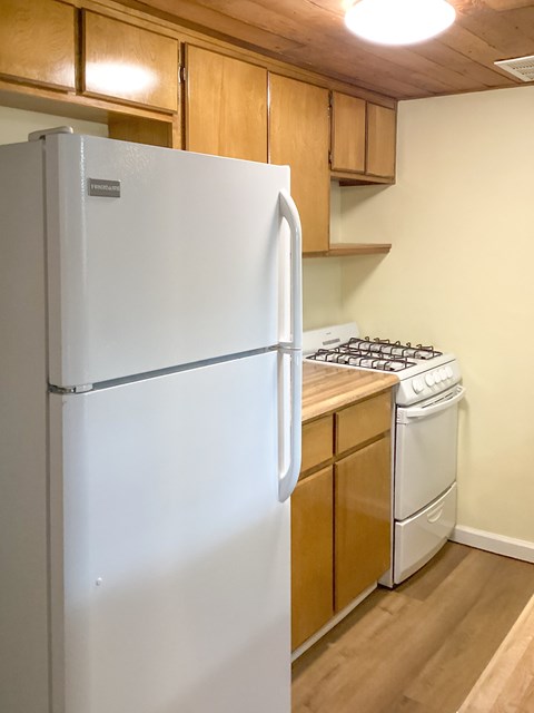 A white refrigerator is in a kitchen with wooden cabinets.