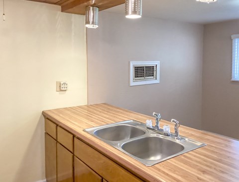 A kitchen with a wooden countertop and a double sink.
