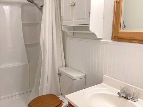 A white bathroom with a toilet, sink, and shower.
