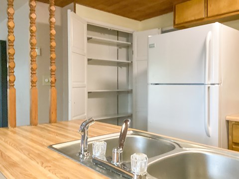 A kitchen with a white fridge and wooden countertop.