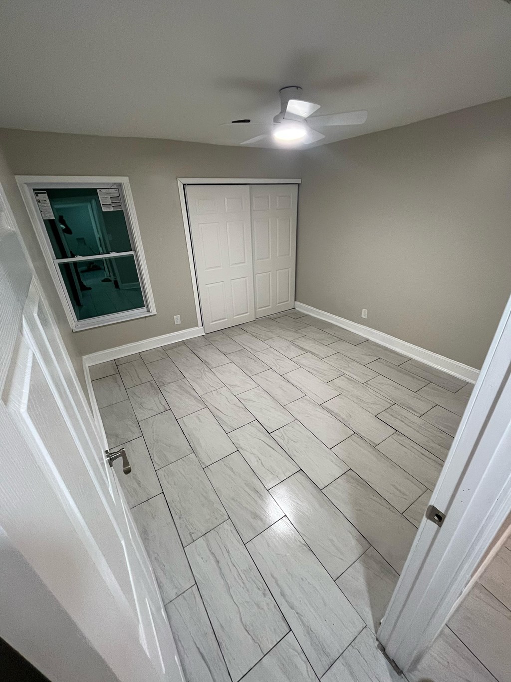 A room with a white ceiling fan and a white door.