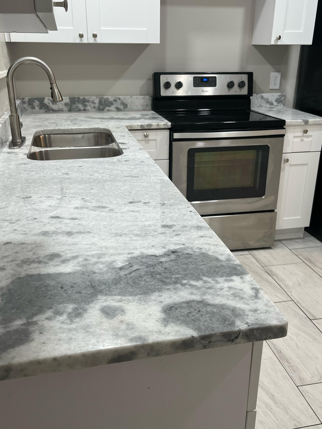 A kitchen with a marble countertop and stainless steel appliances.