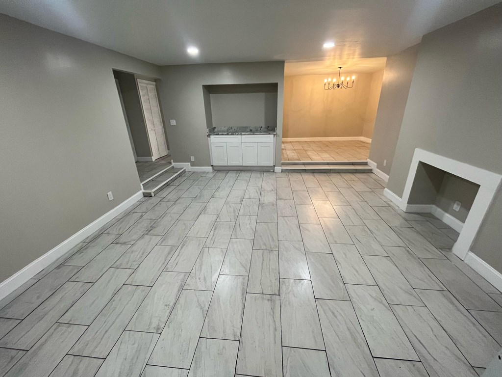 A spacious room with a wooden floor and a chandelier.