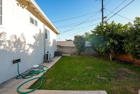 the backyard of a house with a garden and a hose watering the grass