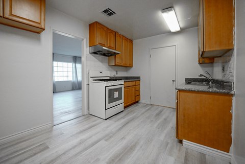 an empty kitchen with white appliances and wooden cabinets