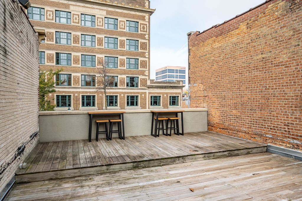 the deck on the top of the building has a table and two stools