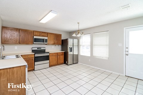 a kitchen with a white tile floor and wooden cabinets and a refrigerator