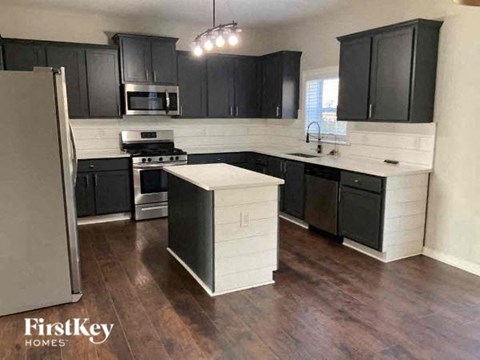 a large kitchen with black cabinets and a refrigerator