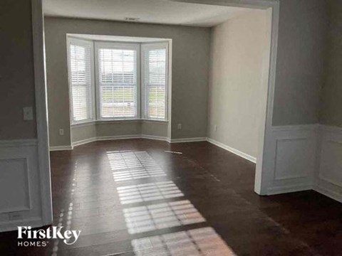 an empty living room with a window and wooden floors