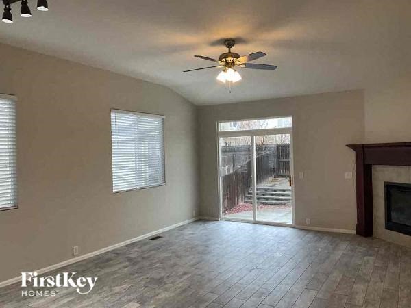 an empty living room with a ceiling fan and a sliding glass door