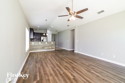 A spacious room with a ceiling fan and wooden flooring.