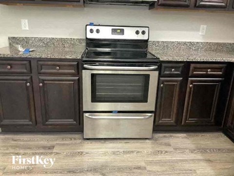 A stainless steel oven with a black glass door is built into a kitchen counter.