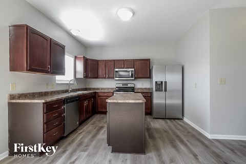 A kitchen with brown cabinets and a stainless steel refrigerator.