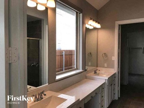 A bathroom with a large mirror, a sink, and a window.