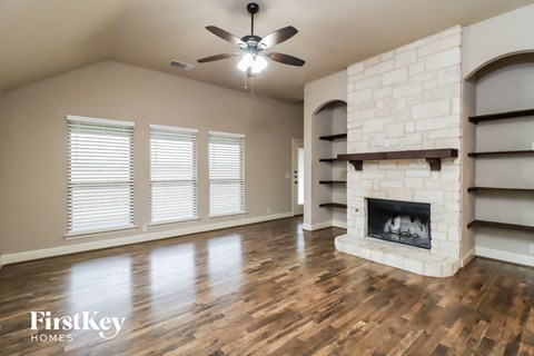 A spacious living room with a fireplace and a ceiling fan.