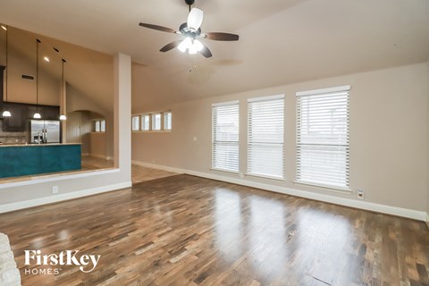 A spacious room with wooden floors and a ceiling fan.