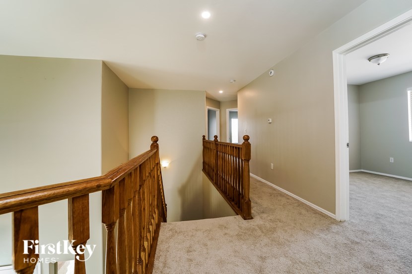 A spacious room with a carpeted floor and a wooden staircase leading to the next level.