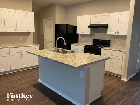 A kitchen with a granite countertop and white cabinets.