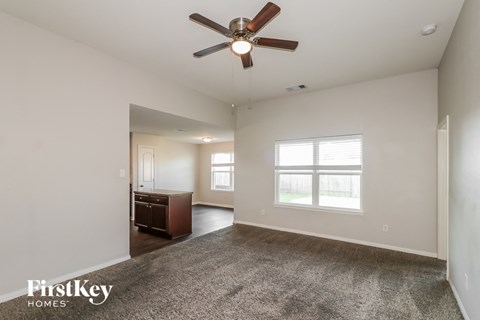 A spacious room with a ceiling fan and a carpeted floor.