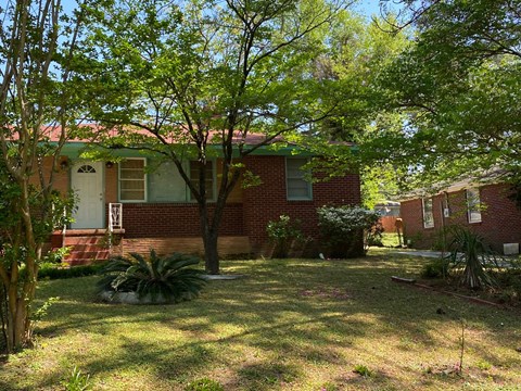 a red brick house with a yard and trees