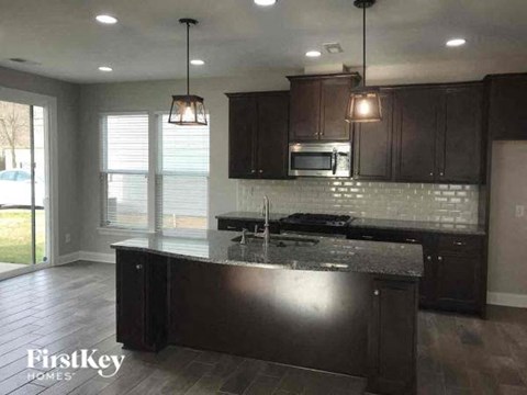 A kitchen with dark brown cabinets and a black countertop.