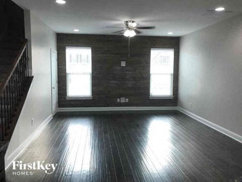 A spacious room with wooden floors and a ceiling fan.